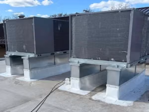 Custom-flashed PVC membrane for commercial RTU curbs on a Michigan facility.