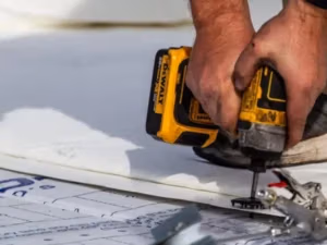 Ideal Roofing technician using a drill to install engineered Duro-Last fasteners into a commercial roof deck.