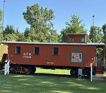 Side view of a red caboose with a white Duro Last roofing system in Owosso, MI that was installed by a roofing contractor that provides installations and repairs beyond just commercial roofing in Flint.