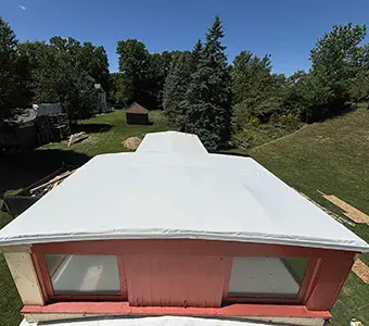 Top view showing roofing and windows of a red caboose with a white Duro Last roofing system in Owosso, MI that was installed by a roofing contractor that provides installations and repairs beyond just commercial roofing in Flint.