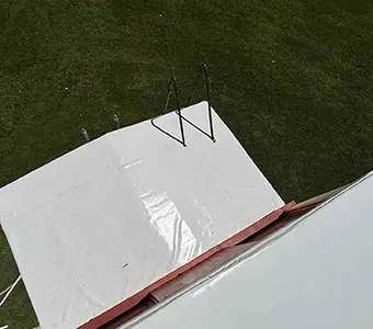 Rear view showing backend of a red caboose with a white Duro Last roofing system that was installed in Owosso, MI by a roofing contractor that provides installations and repairs beyond just commercial roofing in Flint.