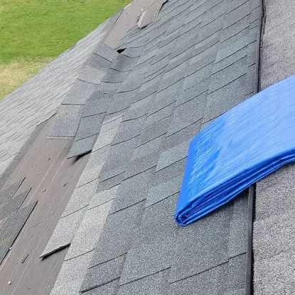 Lapeer Michigan home with wind damaged gray shingles and a blue tarp.