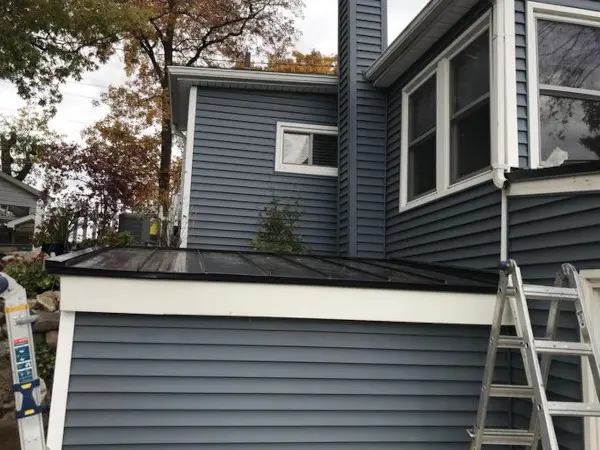 Black standing seam metal roof on a lakeside home with forensic-grade flashing by Ideal Roofing.