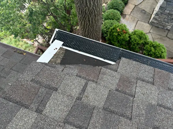 Wind damaged roof of home showing missing shingles just prior to Ideal Roofing completing roof repairs.