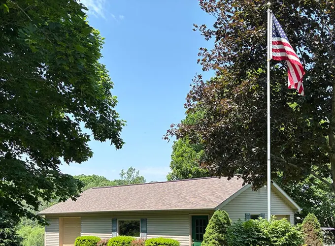 Our residential roofing in Flint provided a new roof replacement for garage sitting in the sunlight with American flag in the yard.
