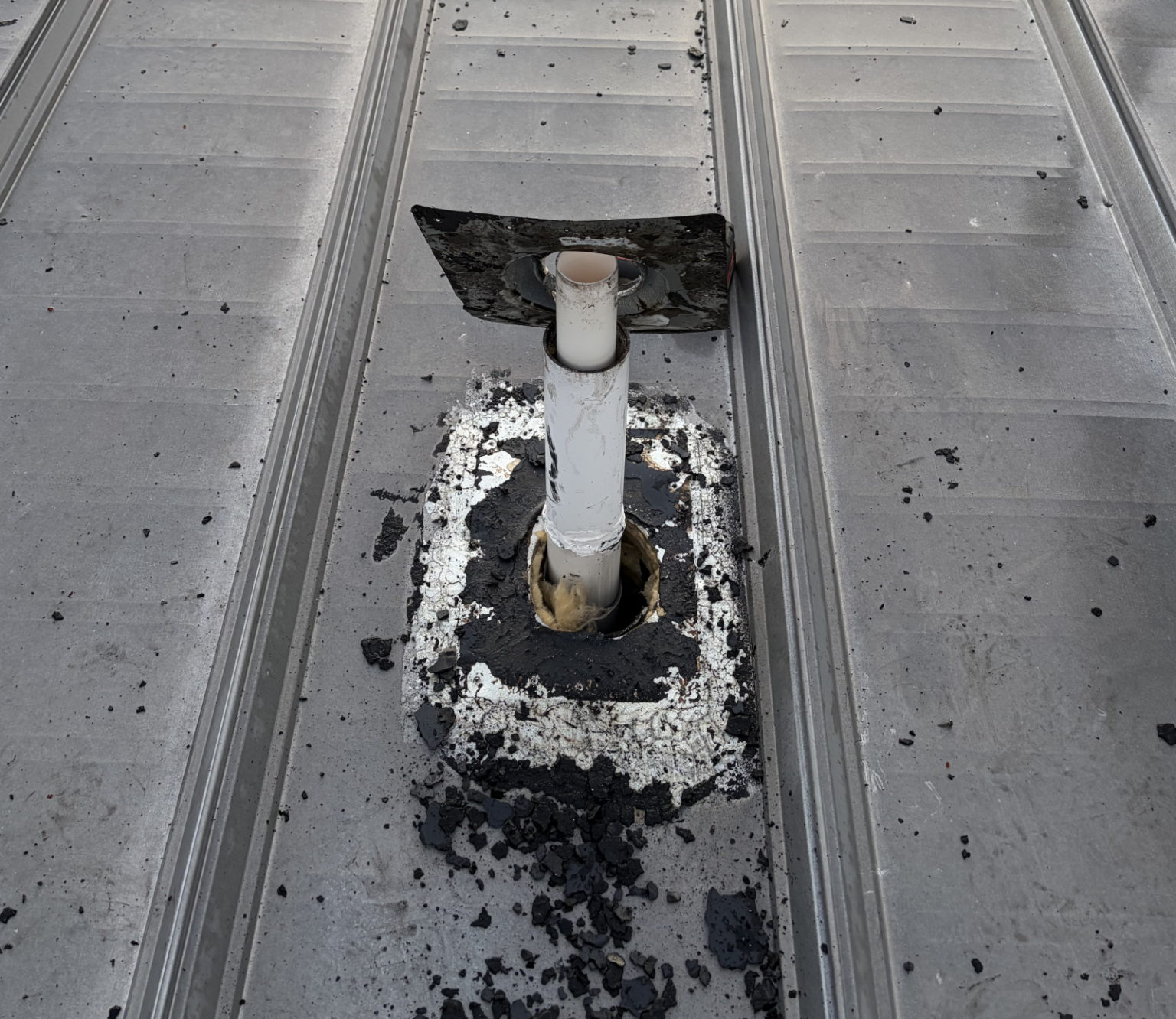 Removal of a rotten roof vent pipe boot exposing the interior of the commercial roof.